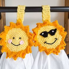 two crocheted sunflowers with sunglasses on them hanging from a clothes rail