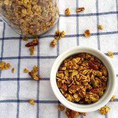 a white bowl filled with granola next to a glass jar full of granola