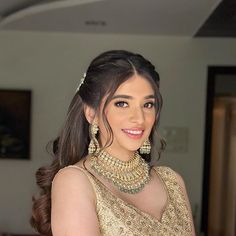 a woman in a gold dress with jewels on her neck and shoulder, smiling at the camera