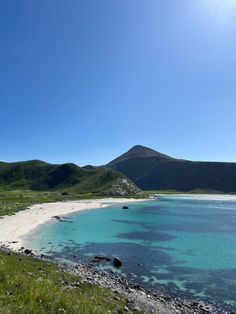 the water is crystal blue and clear with mountains in the background