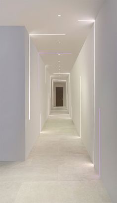 an empty hallway with white walls and purple lighting