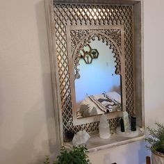 a mirror sitting on top of a table next to a potted plant and vase