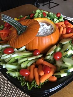 a platter filled with vegetables and dip surrounded by pumpkins, celery, lettuce