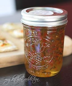 a glass jar filled with liquid sitting on top of a wooden table next to a cutting board