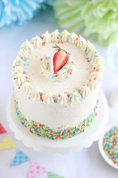 a white cake with sprinkles and a strawberry on top