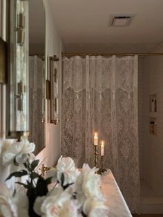 a bathroom with flowers and candles on the counter