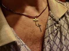 a man wearing a necklace with a cross on it and a gold chain around his neck