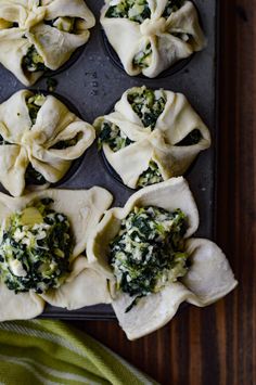 some dumplings with spinach and cheese are on a baking tray next to a green towel