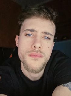 a close up of a person wearing a black shirt and holding a cell phone in his hand