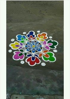 a colorful flower design painted on the side of a road with white circles around it