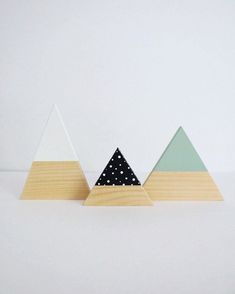 three wooden triangles with polka dots on them in front of a white wall and floor