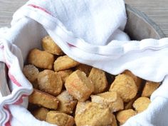 a metal bowl filled with bread cubes on top of a wooden table next to a white towel