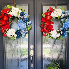 two wreaths with red, white and blue flowers are hanging on the front door