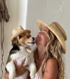 a woman wearing a straw hat and holding a dog