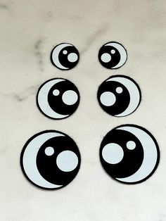 four black and white circles with eyes on them sitting on a marble counter top in front of a tile floor