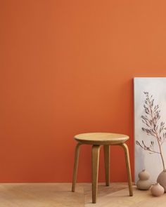 an orange wall with two vases and a small table on the floor next to it