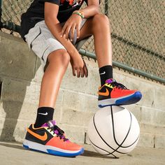 a young boy sitting on top of a basketball next to a white and orange ball