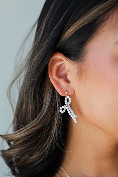 Looking for that final touch for your favorite eye-catching look? We suggest the Blaire White Bow Drop Earrings! These trendy earrings start with a stud post back and fall to beaded bows. Add these fun earrings to a black dress + heels to add a chic touch to your date night look! Gold Plated Beaded Bows Stud Post Back One Size | Length 1.5” Chic Beaded Earrings For Party, Chic Beaded Drop Earrings For Parties, Chic Party Beaded Drop Earrings, Chic Beaded Earrings For Evening, Chic Beaded Evening Earrings, Formal White Jewelry With Decorative Bow, Chic Beaded Earrings For Gift, Formal White Jewelry With Bow Detail, Feminine Formal Bow Earrings