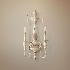 a white wall mounted light with two candles on each arm and one candle in the middle