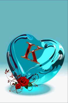 a blue heart shaped object with the letter k on it's side next to a red rose