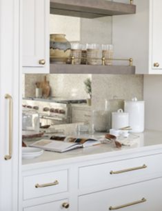 a kitchen with white cabinets and gold handles