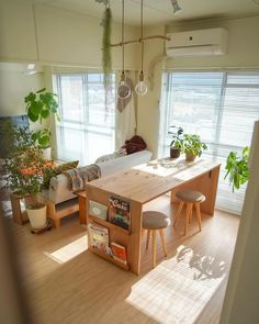 a living room filled with furniture and lots of plants on top of a hard wood floor