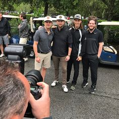 a group of men standing next to each other in front of a golf cart on a road