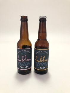 two beer bottles sitting next to each other on a white tablecloth covered surface, one has a label that says hubbox easy up