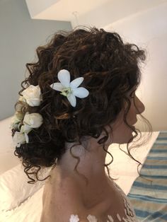 a woman with curly hair and flowers in her hair