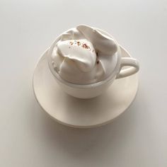 a white cup filled with whipped cream on top of a saucer