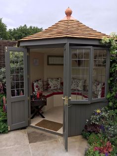 an outdoor room with a bed in the corner and some flowers on the ground next to it