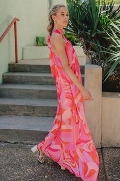 The Josephine Multicolor Printed Halter Maxi Dress is a vibrant and eye-catching garment that exudes summer elegance and playful charm. Its bold color palette of red-orange, pink, and purple creates a stunning visual impact, reminiscent of a tropical sunset or a vivid summer garden in full bloom. Crafted from lightweight fabric, this maxi dress flows effortlessly with every step, offering both comfort and style for warm-weather occasions. The halter neckline of the Josephine dress adds a touch of sophistication while providing support and structure to the silhouette. Its sleeveless design allows for freedom of movement, making it perfect for outdoor events or beachside strolls. A geometric pattern adorns the fabric of the dress, adding depth and visual interest to the overall design. The p Pink Sleeveless Maxi Dress Beach Cover-up, Orange Sleeveless Dress For Summer Parties, Vibrant Summer Maxi Dress For Parties, Vibrant Print Maxi Dress For Spring And Summer Parties, Vibrant Summer Party Maxi Dress, Spring Maxi Dress With Vibrant Print For Summer Parties, Summer Party Vibrant Maxi Dress, Chic Pink Beach Dress For Vacation, Vibrant Sleeveless Maxi Dress With Vibrant Print