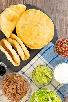 an assortment of mexican food on a plate with dips and sauces next to it