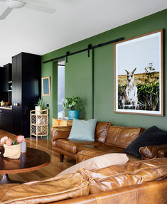 a living room with green walls and leather furniture