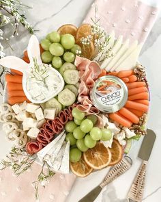 a platter with carrots, grapes, meat and cheese on it next to utensils