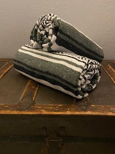 two towels sitting on top of an old trunk in front of a white and black wall