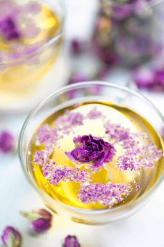 two glasses filled with yellow liquid and purple flowers