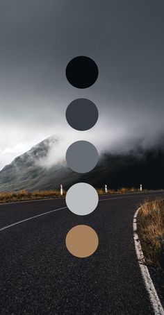 an empty road with three different colored circles hanging from it's sides and mountains in the background