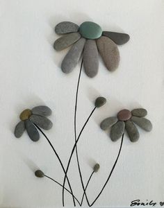 three flowers made out of stones sitting on top of a white wall