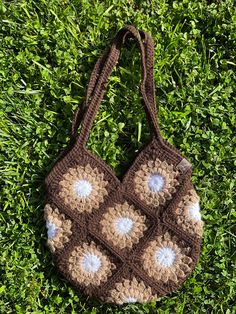 a crocheted brown and white bag laying in the grass