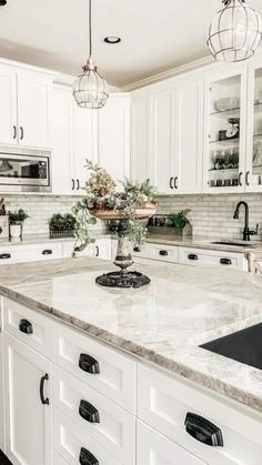 a large kitchen with white cabinets and marble counter tops, along with an island in the middle