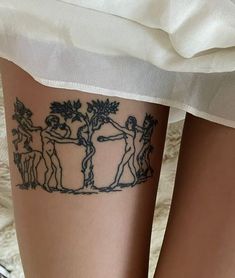 a woman's leg with tattoos on it and two people standing next to each other