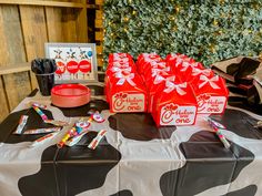 a table topped with lots of red and white bags filled with candy next to a christmas tree