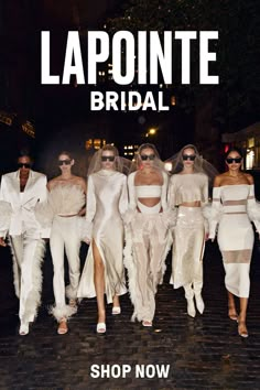 models in white outfits walk down the street at night with one woman wearing sunglasses on her head