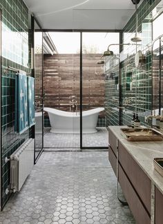 a bathroom with two sinks and a bathtub in the middle, surrounded by green tiles