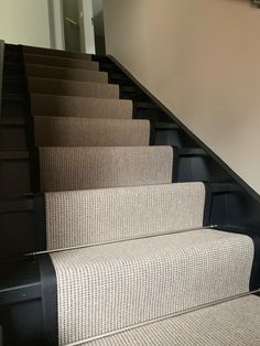 the carpeted stairs are lined with black rails