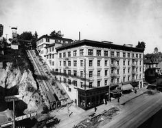 an old black and white photo of a building being built on the side of a hill