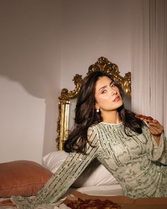 a woman sitting on top of a bed holding a slice of pizza in her hand