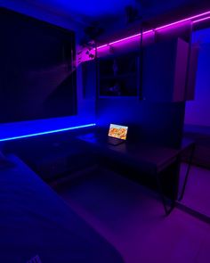 a laptop computer sitting on top of a desk in a room with purple lighting around it