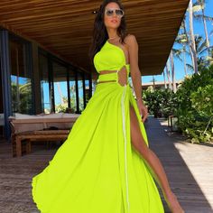 a woman in a neon green dress posing for the camera with her legs slited